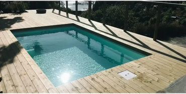 Rektangulär glasfiberpool Saba med turkost vatten och trädeck