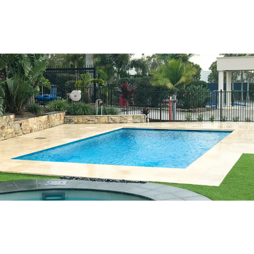 Leisurepools Elite pool med rektangulär form, klart blått vatten, beige stenplattor och gräs