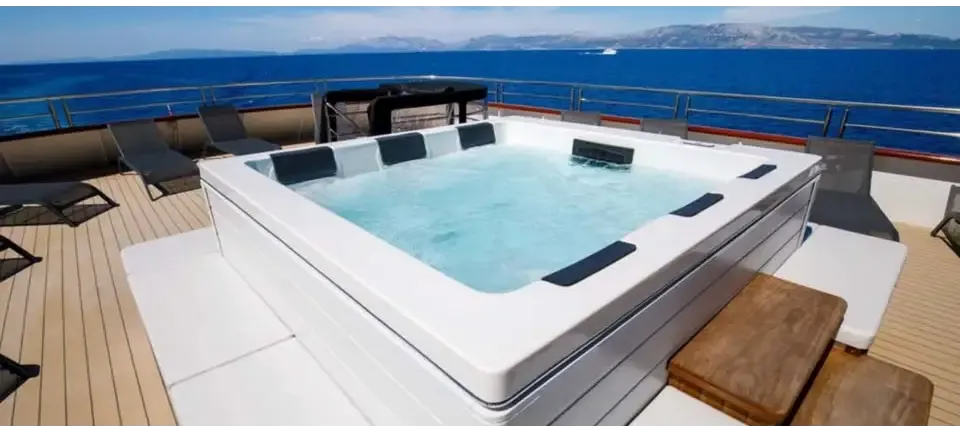 PassionSpa Serene 6 Fire Pit-spabad – hvid overflade, rektangulær form, sorte paneler, klart blåt vand, træterrasse