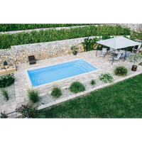 Rektangulär Glasfiberpool Aruba 700 med klart blått vatten, beige stenplattor och grönska