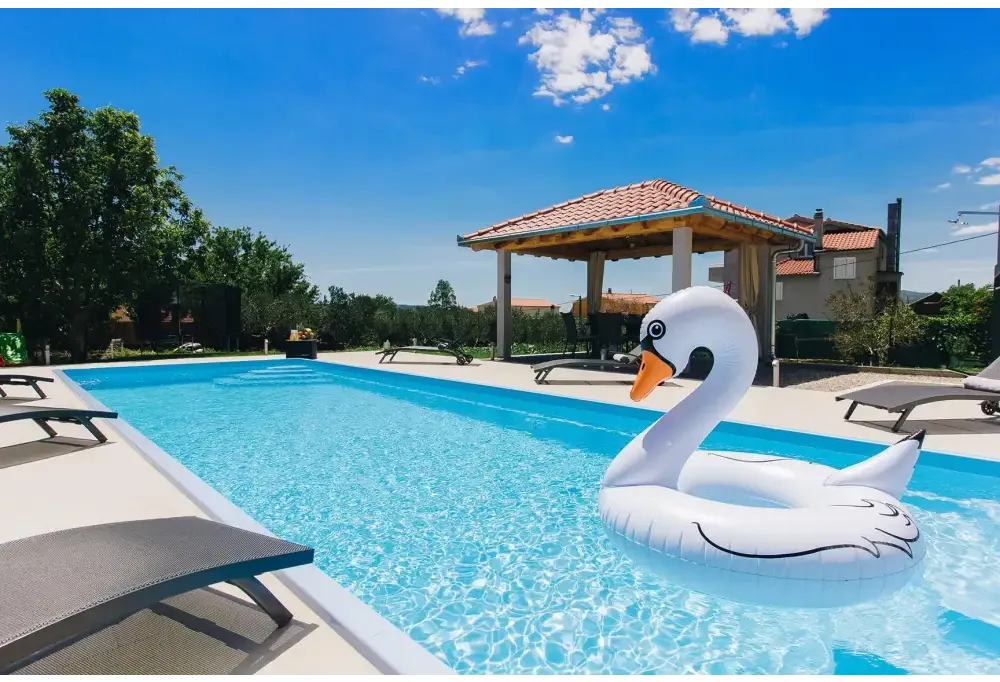 Vit uppblåsbar svanflotte med svart kontur och orange näbb i glasfiberpool Jamaika 25x3 75x1 50m