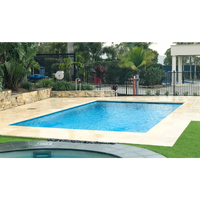 Leisurepools Elite pool med rektangulär form, klart blått vatten, beige stenplattor och gräs