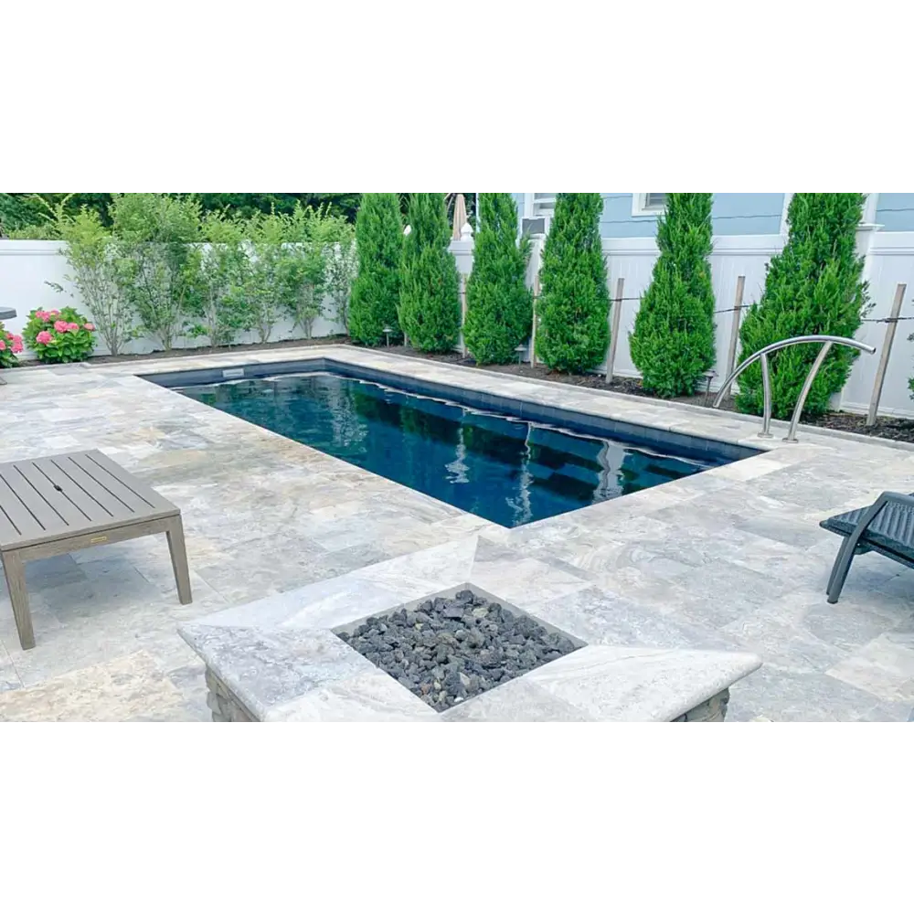 Rektangulär Leisurepools Harmony pool med klart blått vatten, grå sten och gröna träd