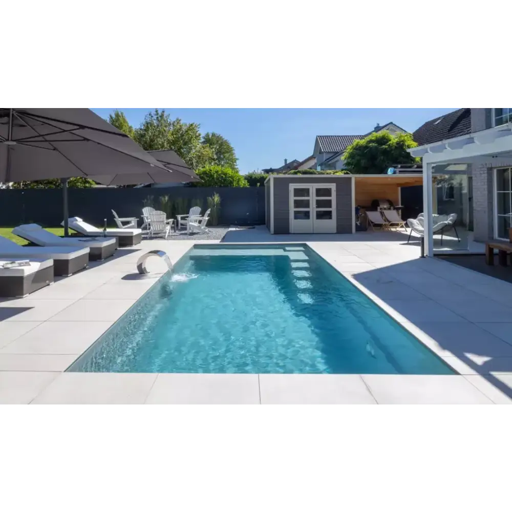 Rektangulär pool med kristallklart blått vatten, modern design, integrerad metallstege och visuellt imponerande hög vattenlinje