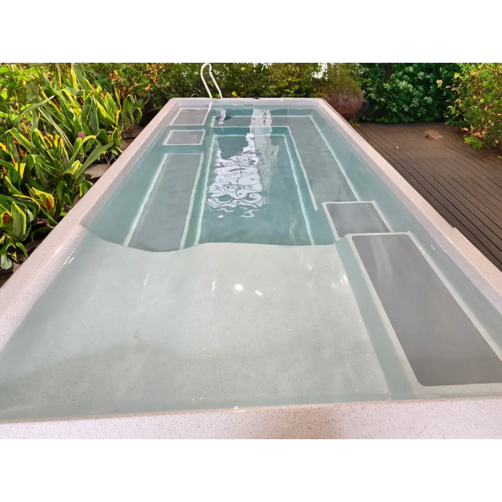 Rektangulär fiberglas wellness pool MIRA390 med ljusgrå interiör och inbyggda steg, omgiven av grönska