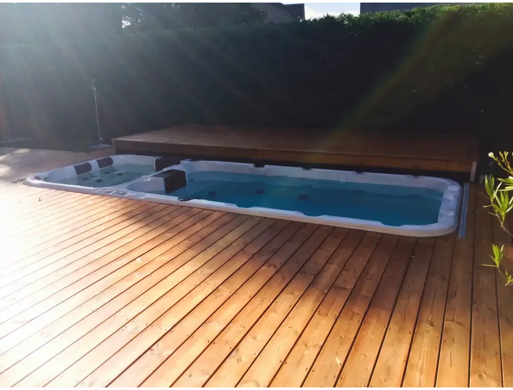 PassionSpa Aquatic 3-swimspa – hvid overflade, blåt vand, sorte siddepladser, træterrasse