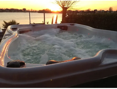 PassionSpa Renew-spabad – hvid overflade, rød LED-belysning, solnedgang over en sø
