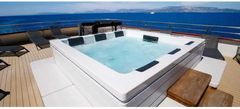 PassionSpa Serene 6 Fire Pit-spabad – hvid overflade, rektangulær form, sorte paneler, klart blåt vand, træterrasse
