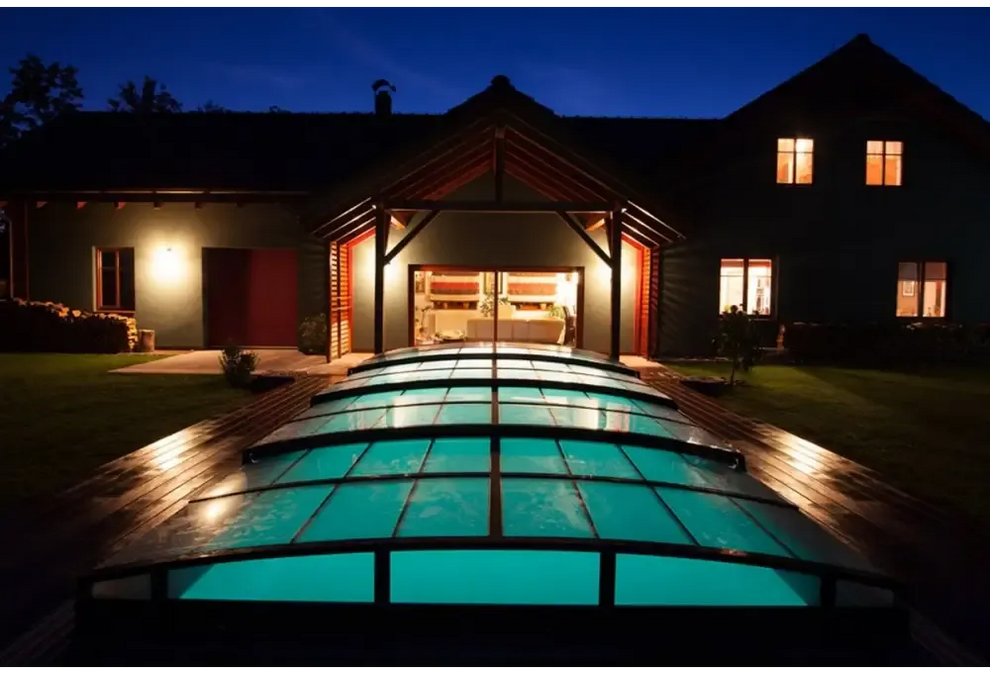 Pooltak Infinity med extra starka profiler: upplyst valvformat glastak över modern pool nattetid