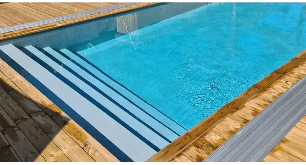 Pooltime Exclusive-pool, 12 mm – rektangulær form, klart blåt vand, træterrasse, grå metaltrin