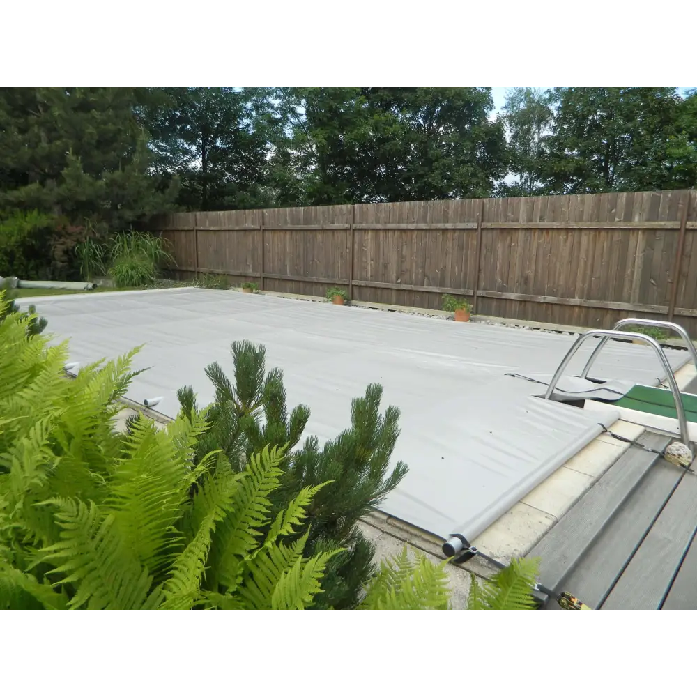 Grå poolöverdrag med metallram, pool inkl handenhet och gröna växter i förgrunden